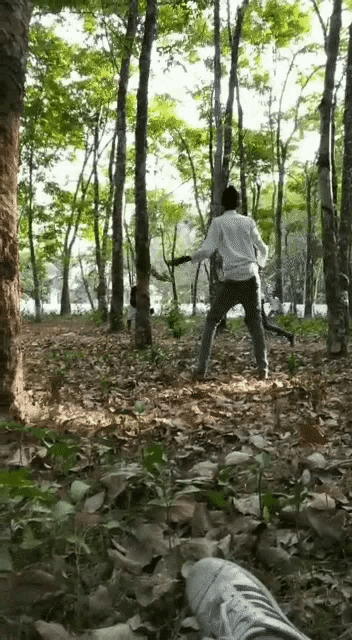 a man in a white shirt is standing in the woods