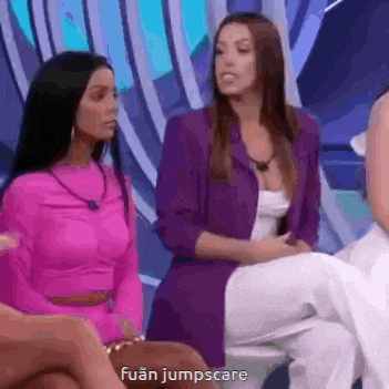 a woman in a pink top and purple jacket is sitting next to another woman in a white dress .