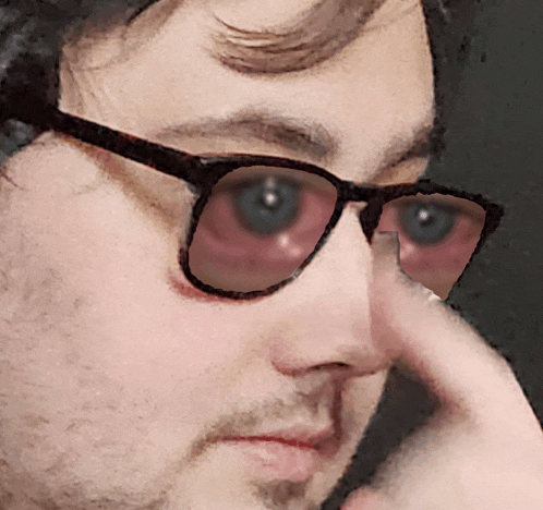 a close up of a man wearing glasses and holding his nose