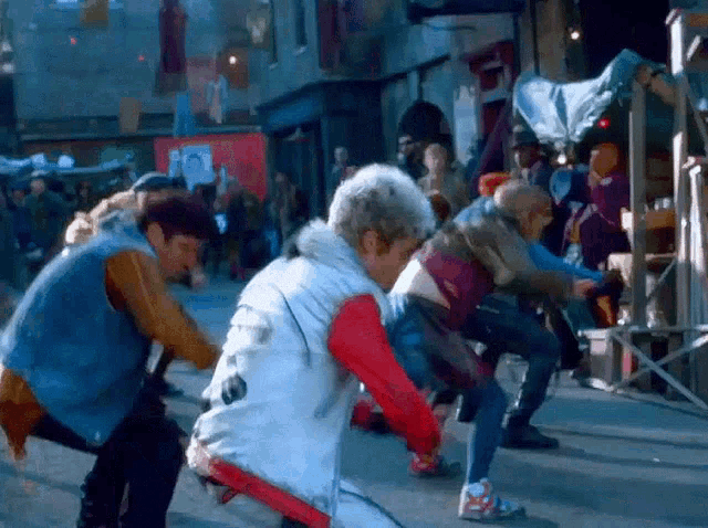 a group of people are dancing on a street in front of a building