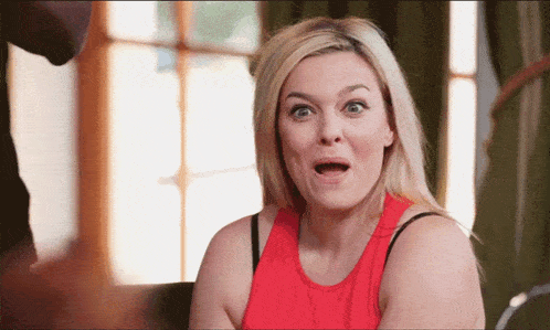 a woman with a surprised look on her face wearing a red tank top
