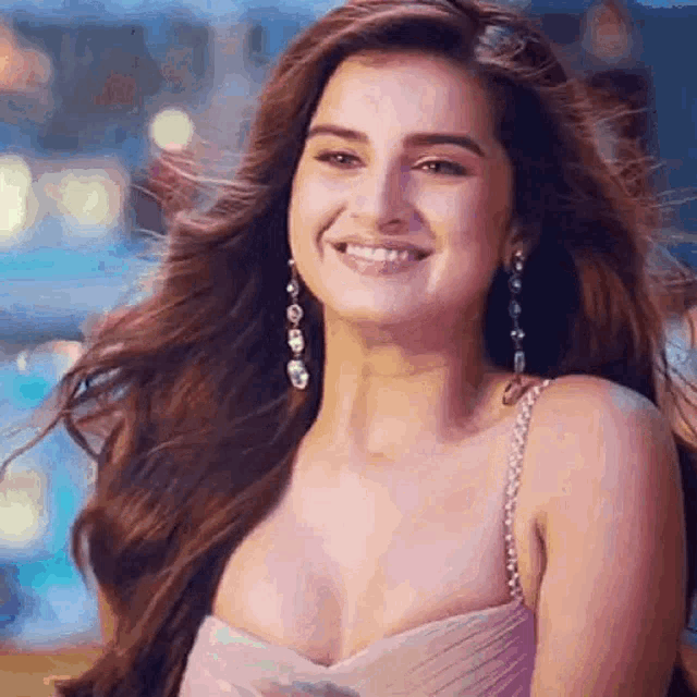 a woman wearing a pink dress and earrings is smiling .