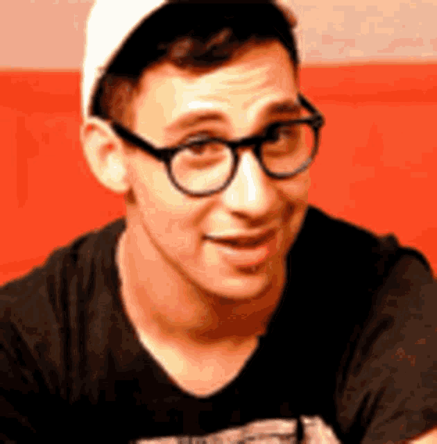 a man wearing glasses and a white hat is smiling