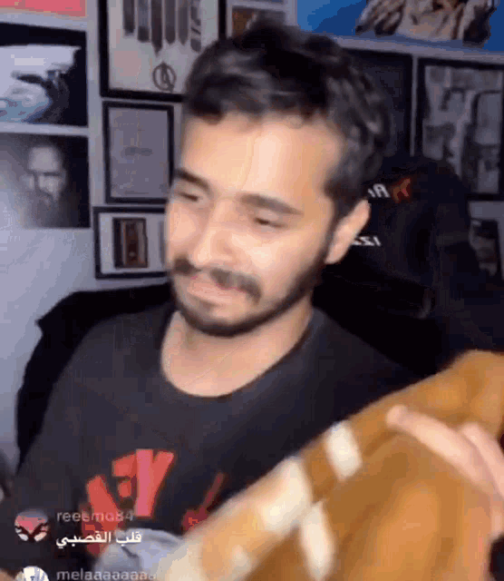 a man with a beard is wearing a black shirt with a red x on it