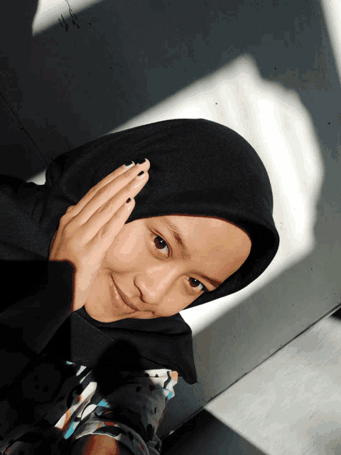 a girl wearing a black hijab is looking at the camera