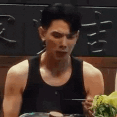 a man in a black tank top is eating food with a fork .
