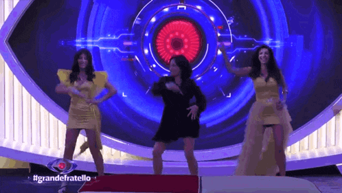 a group of women are dancing on a stage in front of a big eye .