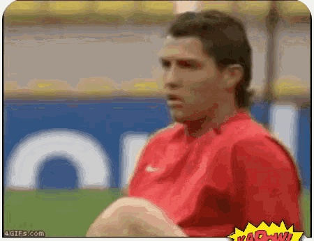 a man in a red shirt is sitting in front of a sign that says ' wow ' on it