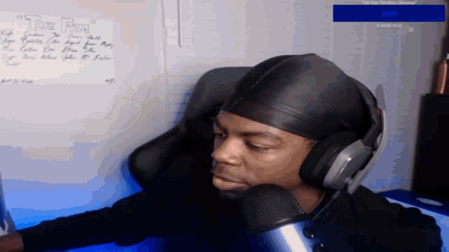 a man wearing headphones sits in front of a microphone with a sign on the wall that says " the pain "