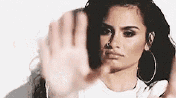 a woman is making a stop gesture with her hand .