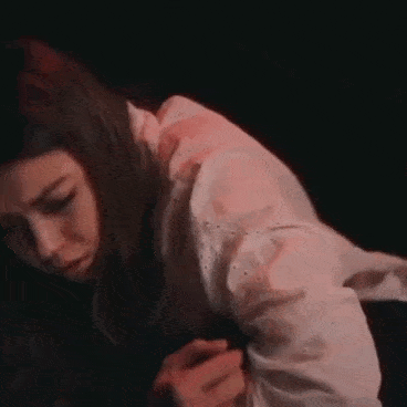 a woman in a white shirt is kneeling down in the dark .