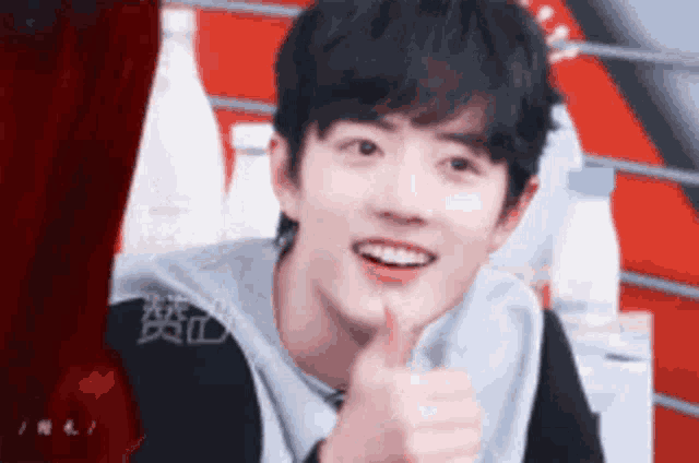 a young man is giving a thumbs up sign while smiling .