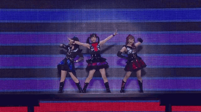 three women are dancing on a stage in front of a screen .
