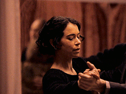 a woman in a black dress is holding a man 's hand while dancing
