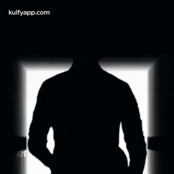 a silhouette of a man standing in the dark with a light behind him .
