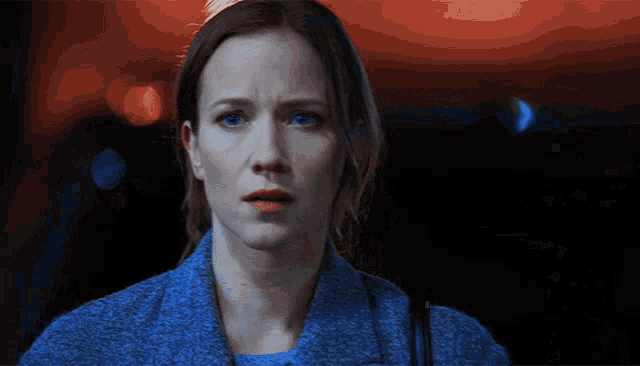 a woman with blue eyes and a blue jacket is looking at the camera