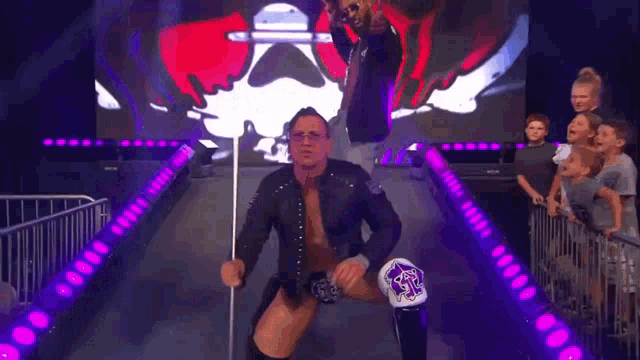 a wrestler is walking through a tunnel with the word inevitable on the screen behind him