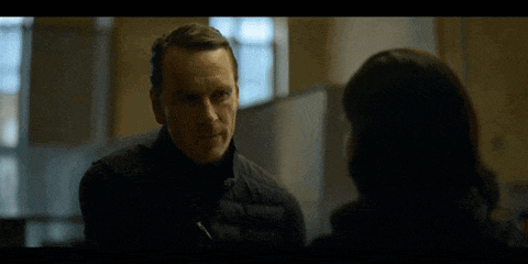 a man and woman are looking at each other in a dark room .