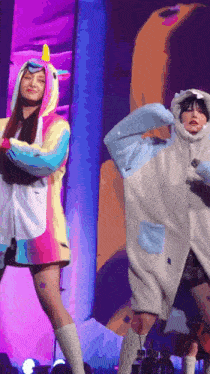 a woman in a unicorn costume is standing next to another woman in a shark costume