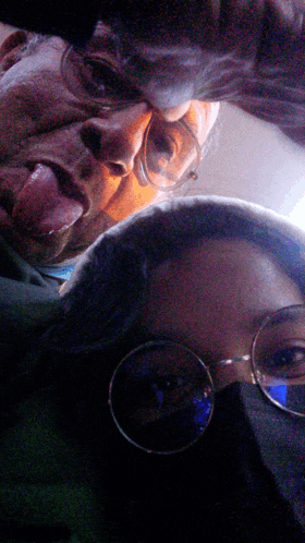 a man with his tongue out and a woman with glasses on
