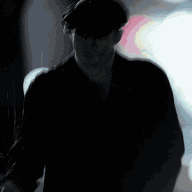 a man wearing a hat and a turtleneck is standing with his arms outstretched