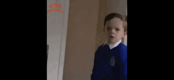 a young boy in a blue shirt and white shirt is standing in front of a door .
