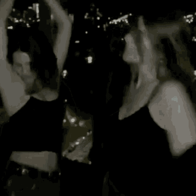 two women are standing next to each other in the dark .