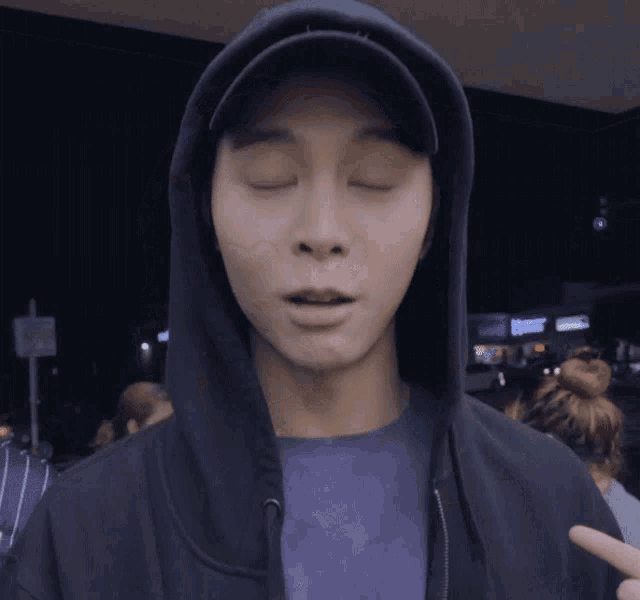 a man with his eyes closed wearing a hoodie and a hat