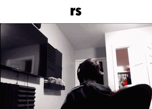 a man wearing headphones is sitting in front of a television and the word rs is on the bottom