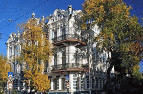 a white building with a balcony and trees in front