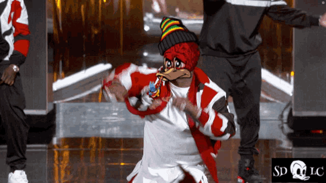 a man in a duck mask is dancing in front of a sd lc logo
