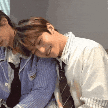 a man in a striped shirt is laying on another man 's shoulders