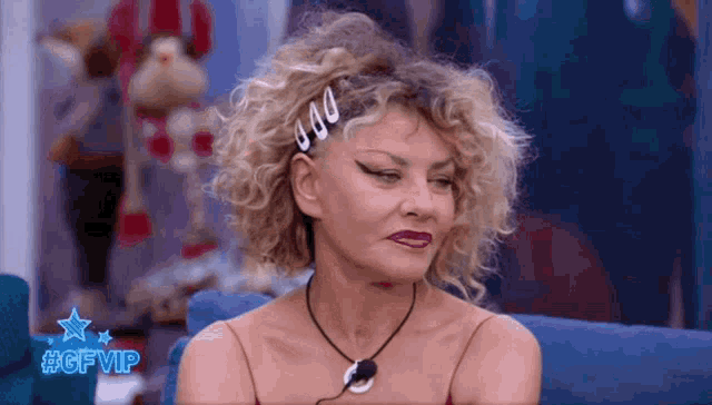 a woman with curly hair is sitting on a blue couch with #gfvip written on the bottom right