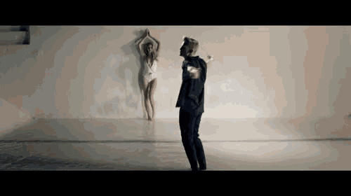 a man is dancing in front of a woman in a bathing suit in a room .