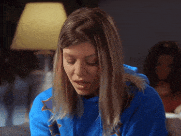 a woman in a blue sweatshirt with a star on it looks down