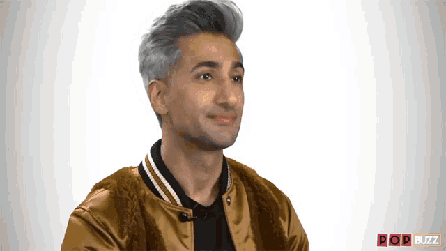 a man with gray hair is wearing a gold jacket and a black shirt ..