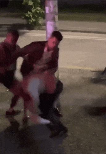 a group of people are fighting on a street