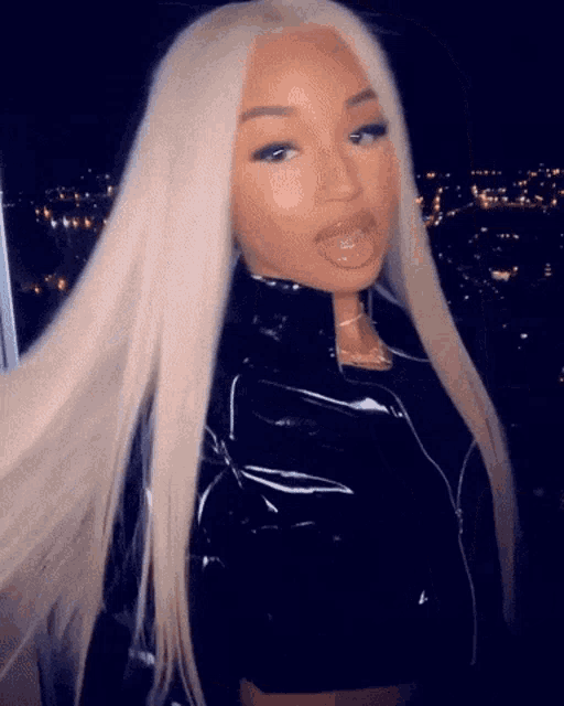 a woman with blonde hair is wearing a black jacket and a black crop top .