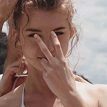 a woman with curly hair is covering her face with her finger .