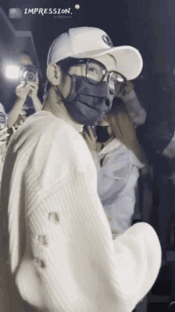 a man wearing a mask and glasses is standing in front of a crowd with the word impression above him