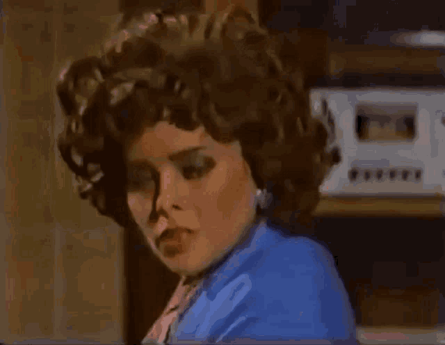 a woman is wearing a blue jacket and a pink scarf and making a funny face .