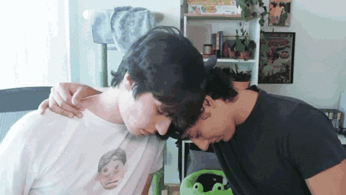 two men are hugging each other and one has a t-shirt that has a face on it