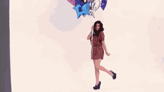 a woman in a dress is holding a bunch of balloons in her hands