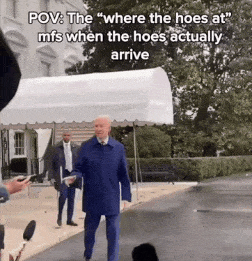 a man in a blue coat is walking in front of a white tent with the caption " where the hoes at "
