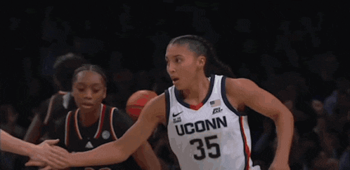 three female basketball players one of whom is wearing a jersey that says conn on it