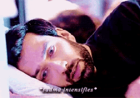 a man with a beard is laying on a bed with the words " sadma intensifies " written above him
