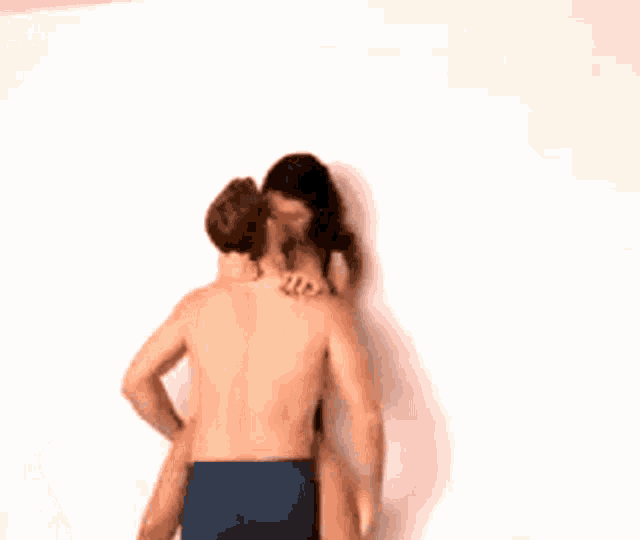 a man and a woman are kissing against a wall