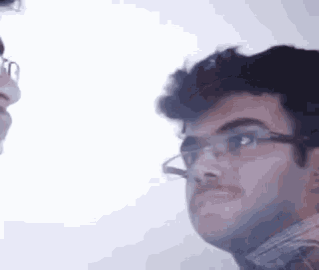 a man wearing glasses and a face mask is looking at another man .