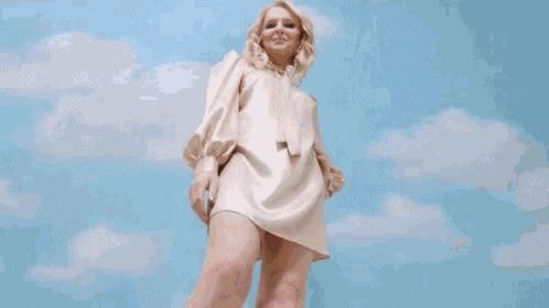 a woman in a short white dress is standing in front of a blue sky .