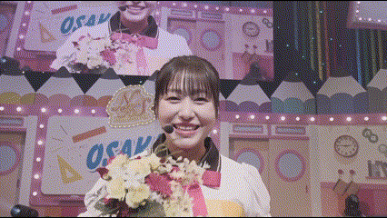 a woman is holding a bouquet of flowers and smiling in front of a screen that says osaka